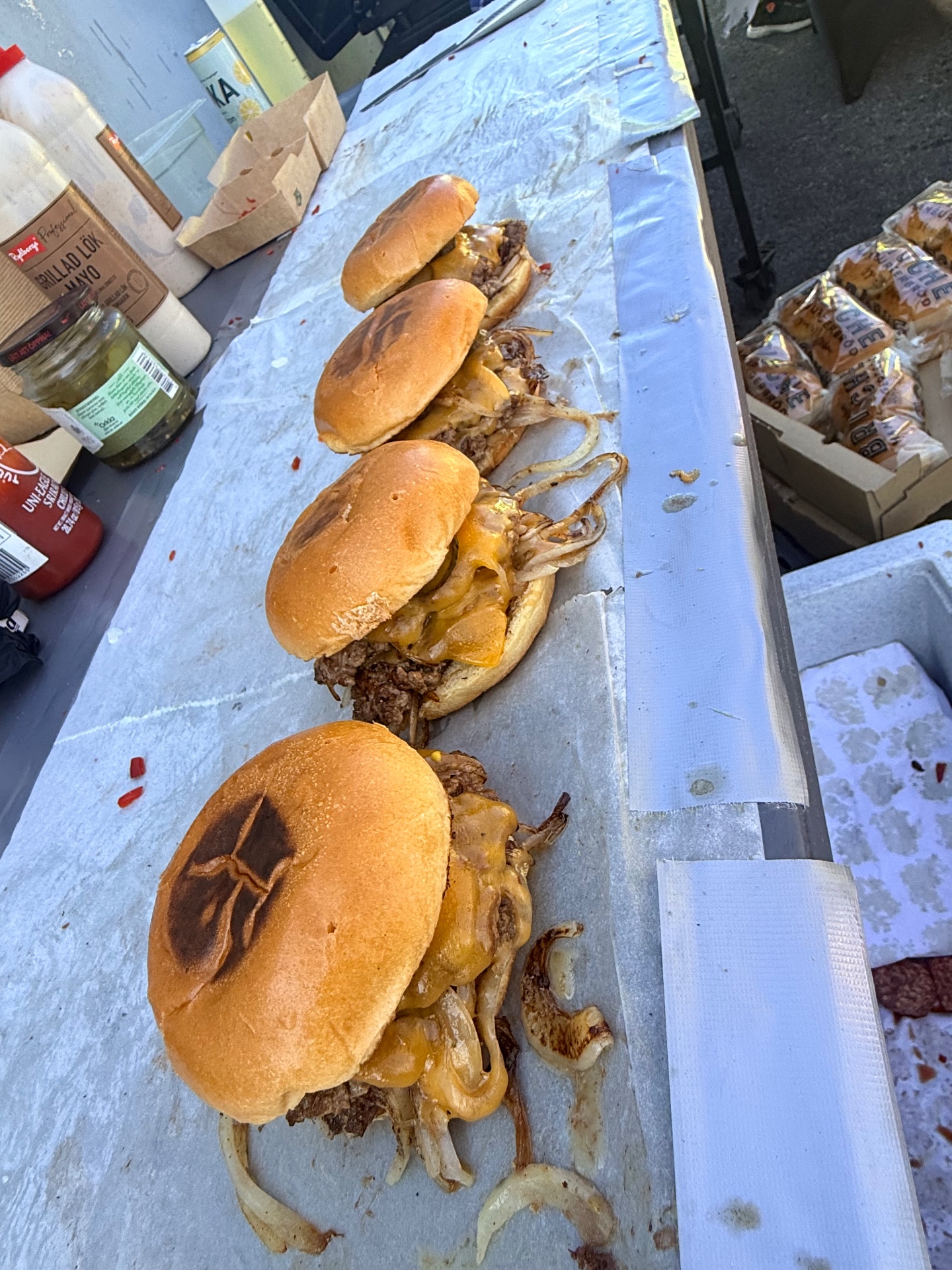 Rad av smashburgare med rostat bröd på arbetsbordet under popup